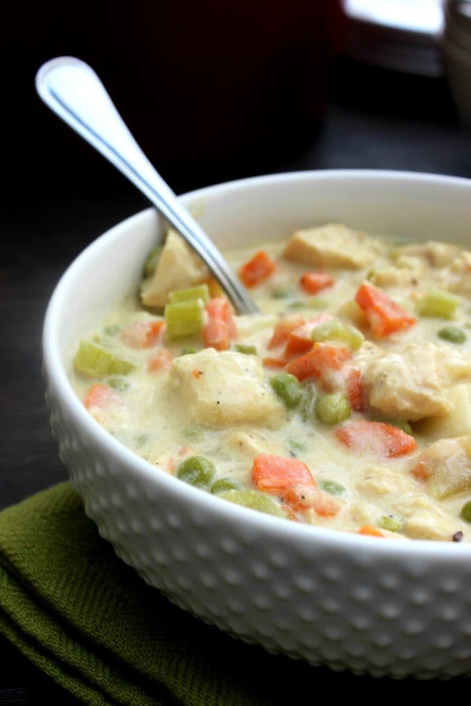 CHICKEN POT PIE SOUP - a deliciously simple soup recipe made from scratch. A fantastic classic comfort food brought to you in a bowl. White bowl with spoon with chicken pot pie soup in it.