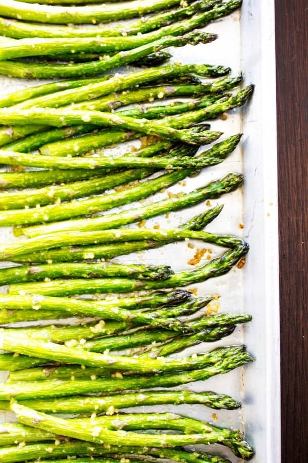 EASY OVEN ROASTED GARLIC ASPARAGUS - a simple & delicious way to prepare & cook asparagus in just under 20 minutes. EASY OVEN ROASTED GARLIC ASPARAGUS - Asparagus on white pan