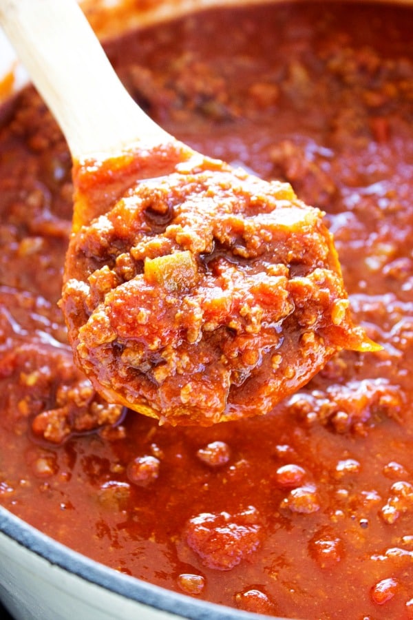 Classic Chili Con Carne - a hearty chili made with beef, onions, salsa, tomato sauce, and green chiles. chili with wooden spoon in pot