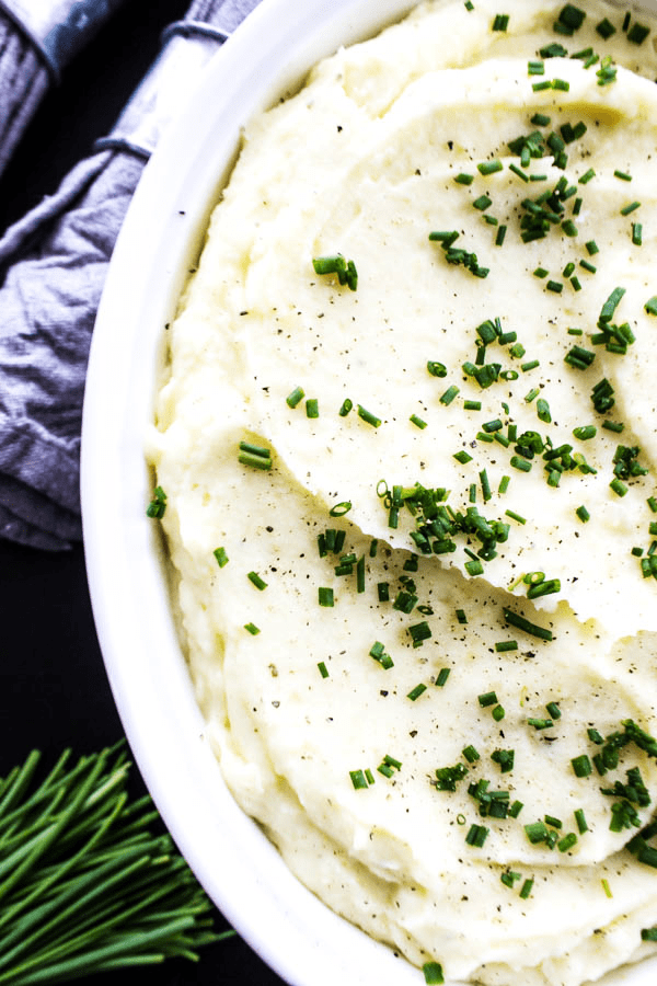 These BEST MASHED POTATOES are light and fluffy, while still rich and creamy; making these the perfect mashed potatoes for any meal or holiday. mashed potatoes served in white baking dish