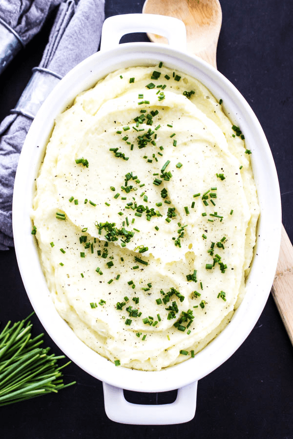 These BEST MASHED POTATOES are light and fluffy, while still rich and creamy; making these the perfect mashed potatoes for any meal or holiday. mashed potatoes topped with chopped chives in white serving dish