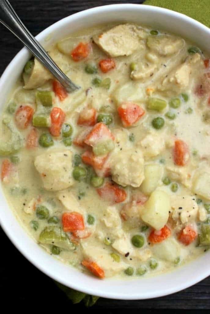 Chicken Pot Pie Soup - a deliciously simple soup recipe made from scratch. A fantastic classic comfort food brought to you in a bowl. Chicken Pot Pie Soup - chicken, green peas, carrots, onions in a bowl.