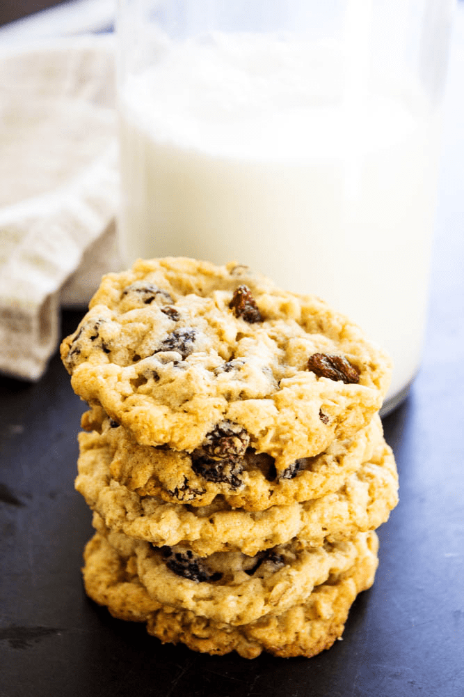 stack of oatmeal raisin cookies with glass of milk