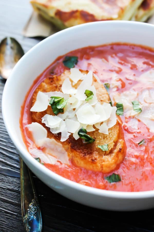 20-MINUTE CREAMY TOMATO BASIL SOUP is a classic comfort food and the is best tomato soup, thanks to 2 secret ingredients. tomato basil soup in white bowl with spoon