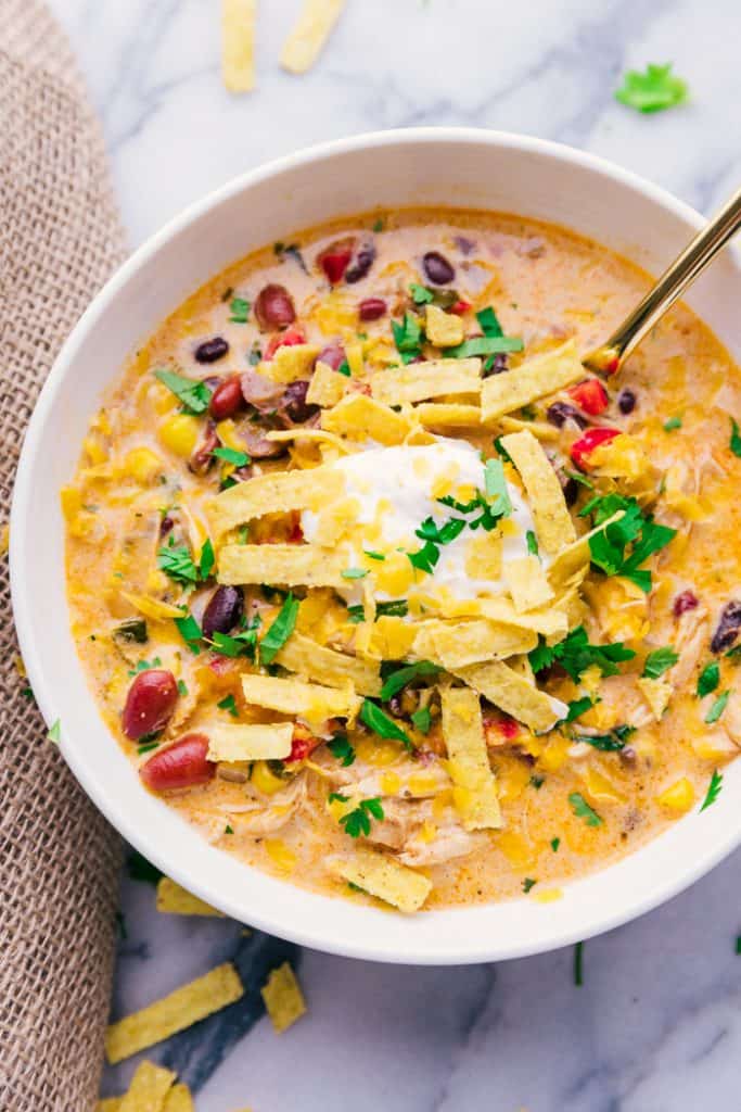 The fall season is the time I love getting out my crock pot and making all things soup. From tomato to this Chicken Tortilla Soup, I love making a simple dinner that my family loves and a meal that can easily feed a crowd. Chicken Tortilla Soup bowl with spoon and garnishes